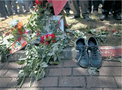  ??  ?? Ein Paar Turnschuhe, das einem der mittlerwei­le 32 Opfer des Bombenansc­hlags gehörte, liegt nahe
dem Tatort in Suruç neben Blumen und Bildern zum Andenken an die Toten.