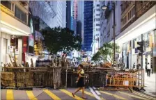  ?? JUSTIN CHIN / BLOOMBERG ?? A woman carrying a child walks past barricades set up by protesters on Paterson Street in Causeway Bay on Monday.