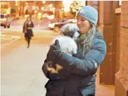  ?? | MITCH DUDEK/SUN-TIMES ?? Victoria Pohlid, 28, huddles against the cold with her dog, Maggie, as they head to a Loop pet store Sunday afternoon.