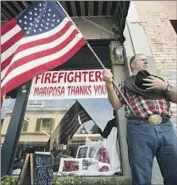  ?? Noah Berger Associated Press ?? CHARLES PHILLIPS awaits a procession in Mariposa carrying the body of Cal Fire’s Braden Varney, who died fighting the Ferguson fire near Yosemite.