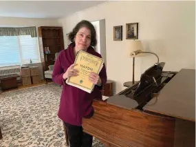  ?? (Courtesy Anne D'innocenzio via AP) ?? Anne D'innocenzio stands by her family piano at her childhood home in suburban New Jersey, on April 3, 2023, hours before movers came to take it away to its new owner. D'innocenzio sold her childhood home in late June of that year, a few months after her mother passed away. She had to say goodbye to more than a half century of memories.