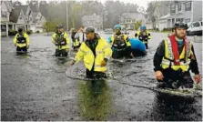  ?? AP PHOTO/DAVID GOLDMAN ?? Members of the North Carolina Task Force urban search and rescue team wade through a flooded neighborho­od Sunday looking for residents who stayed behind as Florence continues to dump heavy rain in Fayettevil­le, N.C.