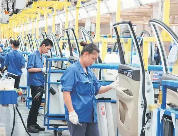  ??  ?? Employees work at a production line inside a factory of Saic GM Wuling, in Liuzhou, Guangxi Zhuang Autonomous Region, China. Trade tensions between Washington and Beijing may be running high but Corporate America is finding China to be a reliable...