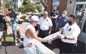  ?? Arnold Gold / Hearst Connecticu­t Media ?? Former flight attendant Paul “Paulie” Veneto, center, who is pushing an airline beverage cart from Boston to New York as a tribute to flight attendants and crew killed in the 9/11 attacks, is presented with a West Haven Fire Department T-shirt by Deputy Chief Bill Johnson, right, during a stop at the Center Fire Station on Elm Street in West Haven on Thursday.