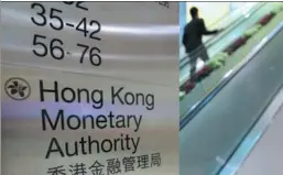  ?? TYRONE SIU / REUTERS ?? A man rides an escalator near a directory board at the Hong Kong Monetary Authority, the city’s de