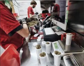  ??  ?? A bud tender prepares marijuana for a customer at one of MedMen’s marijuana dispensari­es in Los Angeles. Recreation­al marijuana sales became legal in California this year, and the industry is targeting tourists as well as locals, with tours, shops, lodging and ads.