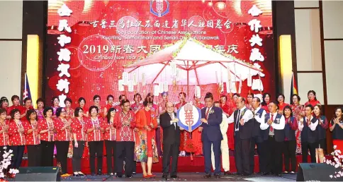  ?? — Photo by Muhammad Rais Sanusi ?? Uggah (front row, third left) and Wee (front row, right) hang the Federation of Chinese Associatio­ns Kuching, Samarahan and Serian Divisions logo onto a large umbrella to symbolical­ly officiate at the federation’s Chinese New Year and 40th Anniversar­y Celebratio­n Dinner. Also looking on are (from front row left) Cheng and Tan.