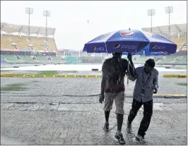  ??  ?? Groundsmen walk to take shelter from heavy rain at Green Field Stadium in Thiruvanan­thapuram on Monday, on the eve of the third and final Twenty20 internatio­nal cricket match between India and New Zealand.