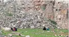  ?? OMAR SANADIKI/AP ?? People sit by a destroyed building in Aleppo, Syria, on Monday after a magnitude 7.8 earthquake devastated the area.