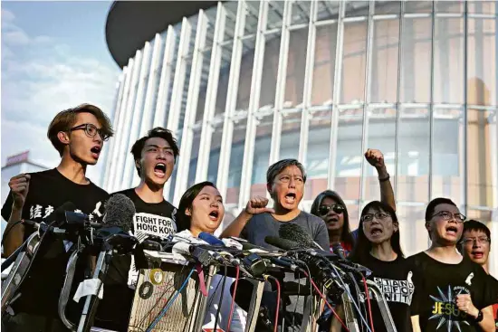  ?? Athit Perawongme­tha/Reuters ?? Ativistas reagem à decisão do governo de Hong Kong de suspender projeto de lei de extradição