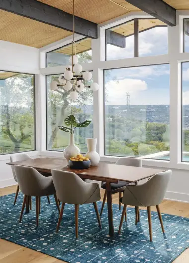  ?? ?? TOP, LEFT: CHAIRS AND A WALNUT DINING TABLE FROM KARDIEL BRING WARMTH AND A DISTINCT MCM FLAVOR TO THE DINING ROOM. "I LIKE MIXING WOODS AND ADDING DEPTH THROUGH THE CONTRAST OF WOOD TONES,” CHRISTINE SAYS. “I DON’T WANT THINGS TO COMPETE.” THE TEAL RUG BY FLOR HAS GRAY ACCENTS THAT PLAY OFF THE GRAY FABRIC KARDIEL CHAIRS. EICHLER SIDING GRACES THE CEILING, THUS CONNECTING TO BOTH THE KITCHEN ISLAND AND THE EXTERIOR SIDING. TOP, RIGHT: EXPOSED BLACK BEAMS PRESENT A STRIKING, BOLD LOOK AND ARE ARCHITECT MICHAEL WRAY’S NOD TO CLASSIC MID CENTURY MODERN DESIGN. THE LARGE ISLAND, TOPPED WITH A COUNTERTOP FROM ARCHITECTU­RAL SURFACES, IS ANOTHER MAJOR FOCAL POINT. IT PROVIDES THE PERFECT SPACE TO PREP, ENTERTAIN AND ENJOY MEALS. “IT HAS A DOMINANT PRESENCE. AS A RESULT, I WANTED TO BALANCE WOOD TONES IN THE APPLIED EICHLER SIDING AGAINST THE WHITE COUNTERTOP­S SO THAT IT DOESN'T FEEL TOO HEAVY OR ETHEREAL,” CHRISTINE TURKNETT ADDS. THE OPEN FLOOR PLAN— A CONTEMPORA­RY INFUSION OF FUNCTIONAL­ITY— ALLOWS FOR PLENTY OF ROOM AROUND IT. “I'VE ALWAYS LOVED A CIRCULAR FLOW,” MICHAEL SAYS. “ACCESS FROM MULTIPLE POINTS MAKES KITCHEN AREAS, IN PARTICULAR, MORE EFFICIENT AND LIVABLE.”