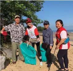  ??  ?? Hamid Bugo (left) and Norma (right) pose for the camera while collecting rubbish along Camp Permai’s Beach 1. With the two are Smart Reader Kids franchisee­s Sharon Chang (second left) who runs the Jalan Kereta Api branch, and Jakiah Sahari who handles the Taman Yen Yen branch.