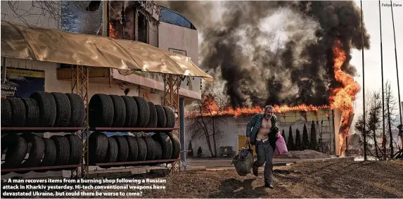  ?? Felipe Dana ?? > A man recovers items from a burning shop following a Russian attack in Kharkiv yesterday. Hi-tech convention­al weapons have devastated Ukraine, but could there be worse to come?