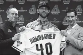  ?? ASSOCIATED PRESS ?? NEWLY ACQUIRED Arizona Diamondbac­ks pitcher Madison Bumgarner (center) holds his new jersey with manager Tory Lovullo (left) and general manager Mike Hazen (right) during a press conference Tuesday in Phoenix.