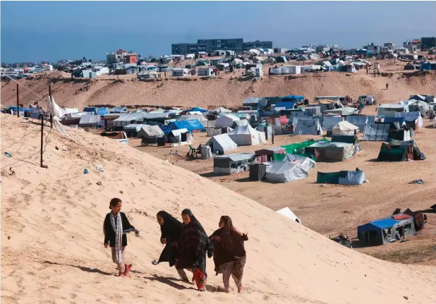  ?? — AFP ?? Palestinia­n girls walk up a sandy hill next to a makeshift tent camp for displaced people in Rafah in the southern Gaza Strip on Thursday, amid the ongoing conflict between Israel and the militant group Hamas.