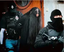  ?? Foto: Profimedia, AFP ?? Policisté vedou od soudu Alenu Zsuzsovou. Tvář si kryje dlouhými vlasy.