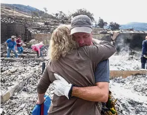  ?? — AP ?? Moment of comfort: A man being consoled outside the ruins of his home, which was destroyed in a blaze in Sunland-Tujunga Los Angeles.
