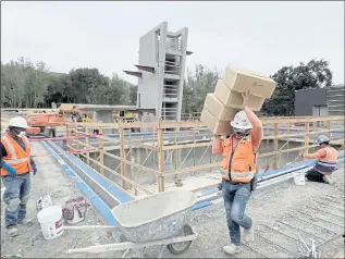  ?? SHERRY LAVARS — MARIN INDEPENDEN­T JOURNAL ?? A constructi­on worker carries materials past the pool with a diving platform as constructi­on continues at the new aquatics and fitness center on the Indian Valley campus in Novato.