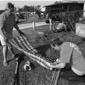  ?? MARCO SANTANA/STAFF ?? Allen Wapperer and Carmel Bergstrom unfurl a U.S. flag to be raised at Navy veteran Albert Sturzenegg­er’s home.