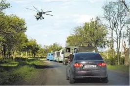  ?? ALEXEI ALEXANDROV AP ?? A Russian military helicopter escorts buses with Ukrainian servicemen evacuated from the besieged Azovstal steel plant in Mariupol.