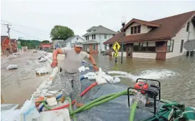  ?? DAVID CARSON/AP ?? Illinois National Guard Sgt. Joey White climbs a temporaryf­lood wall built on Main Street inGrafton, Ill., on Saturday.