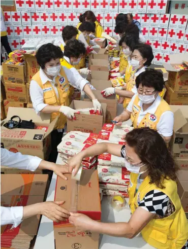  ?? Foto: dpa/Yonhap ?? Frauen des Roten Kreuzes in Südkorea verpacken Lebensmitt­el für Menschen, die in Quarantäne zu Hause sind.