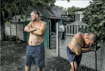  ?? Mauricio Lima / New York Times ?? Residents hang out in front of a destroyed home where a woman died after shelling in Donetsk. Government forces are closing in on insurgents in the city, and most of the streets are deserted.