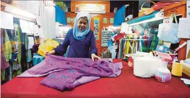  ??  ?? Rosila sibuk menyiapkan tempahan baju pelanggan yang mula diambil pada Disember sehingga akhir Februari lalu bagi mengelakka­n kesuntukan masa.