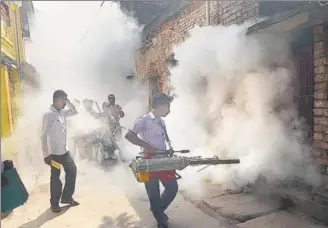  ?? PTI FILE ?? Municipal workers fumigate the streets in Kolkata to check the spread of dengue fever.