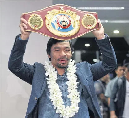  ??  ?? Manny Pacquiao holds his welterweig­ht title belt after defeating Mexican boxer Jessie Vargas.