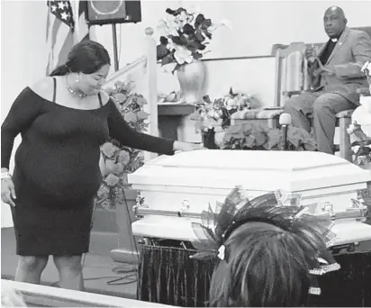  ?? AMY DAVIS/BALTIMORE SUN ?? Melissa Lawson touches the casket of her nephew, Malachi Lawson, on Tuesday at Mount Zion Apostolic Faith Church.