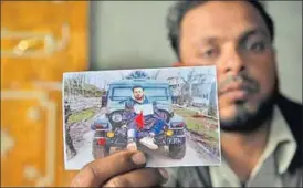  ?? WASEEM ANDRABI /HT ?? Farooq Dar, who was used as a human shield by the Army, holds a picture of him being tied to a jeep at Chill village in Budgam district.