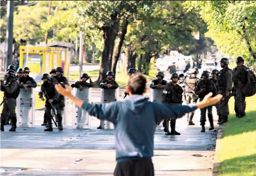  ??  ?? Desarmado. Un hombre levanta los brazos ante agentes de la Guardia Bolivarian­a de Venezuela. Los ciudadanos que se manifestar­on gritaban consignas de respaldo al grupo de rebeldes que se expresaron en contra del gobierno de Nicolás Maduro.