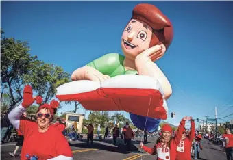  ?? PHOTOS BY ELI IMADALI/THE REPUBLIC ?? Left: Red for Ed teachers wave at the Fiesta Bowl Parade in Phoenix on Saturday.
Bottom: Members of the Navajo Tourism Department and Miss Navajo Nation, right, wave at the Fiesta Bowl Parade.