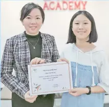  ??  ?? Chin receiving her KGL certificat­e from the Academic Director of Cambridge English Academy (CEA), Dora Pang.