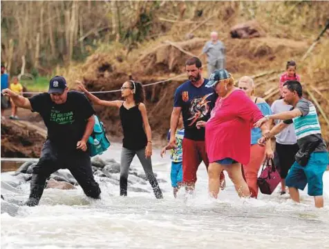  ?? AFP ?? People wade into the San Lorenzo River after a bridge was swept away by Hurricane Maria in Morovis, on Thursday. US military and emergency relief teams ramped up their aid efforts for Puerto Rico amid growing criticism of the response to storms.