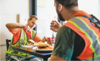  ?? Gabrielle Lurie / The Chronicle ?? Justin Harrison (left) and Spencer McKevitt chow down at the casual 26-seat restaurant Delegates, which serves sandwiches and all-day breakfast items.