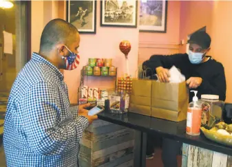  ?? Paul Chinn / The Chronicle 2020 ?? DoorDash driver Ali Badani waits as Hamel Belayadi packs a delivery order at Cafe Encore.