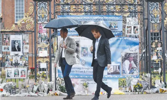  ?? Picture: AFP ?? Prince William and his younger brother Prince Harry walk away after looking at tributes to their mother, Princess Diana, left at Kensington Palace.