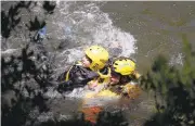  ?? ELLIOTT ALMOND/STAFF ?? Tethered by a rope, Nicky Bunn holds onto Dede Gordon during a swift water rescue drill Thursday performed by Yosemite Search and Rescue in the Merced River.