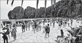  ?? SAKCHAI LALIT/AP ?? Tourists enjoy the beach on Thailand’s Maya Bay shortly before it closed earlier this year.