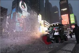  ?? MARK LENNIHAN — THE ASSOCIATED PRESS ?? A tractor with a power brush clears snow Thursday in New York’s Times Square.