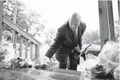  ?? STAFF FILE ?? Former U.S. Rep. Elijah Cummings of Baltimore rearranges flowers left on the stairs at the house where his nephew, Christophe­r Cummings, was shot to death.