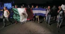  ?? AP PHOTO/MOISES CASTILLO ?? Central American migrants traveling with a caravan to the U.S. walk holding national flags from Mexico and Honduras, as they make their way to Mapastepec, Mexico, Wednesday.