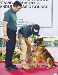  ??  ?? Drug-sniffing dog Odel’s handler puts a medal around his neck as PDEA chief Aaron Aquino looks on during a ceremony honoring 14 narcotics detection dogs in Antipolo, Rizal yesterday.