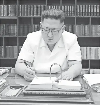  ?? AFP/GETTY IMAGES ?? North Korean leader Kim Jong Un signs documents for the test launch of an interconti­nental ballistic missile. He is the third generation of his family to rule the isolated country.