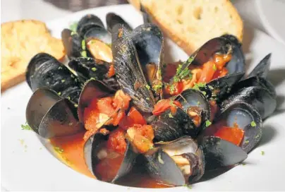  ?? CARLINE JEAN/SUN SENTINEL ?? Diners can’t get enough of the garlicky tomato sauce on the Zuppa di Mussels at Positano Italian Restaurant in Boca Raton.