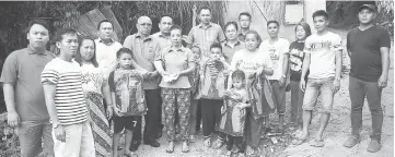  ??  ?? Abong (sixth left) hands over the RM1,000 cash assistance to Jelawai. Also seen are other victims of the fire.