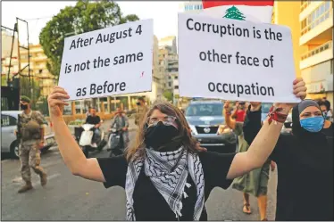  ??  ?? A Lebanese activist holds up placards as she marches during a protest near the Parliament speaker’s house.