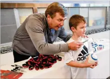  ??  ?? Georgia head coach Kirby Smart gives 5-year-old Preston Parham a football and a sharpie and then sends him over to his players to collect autographs.